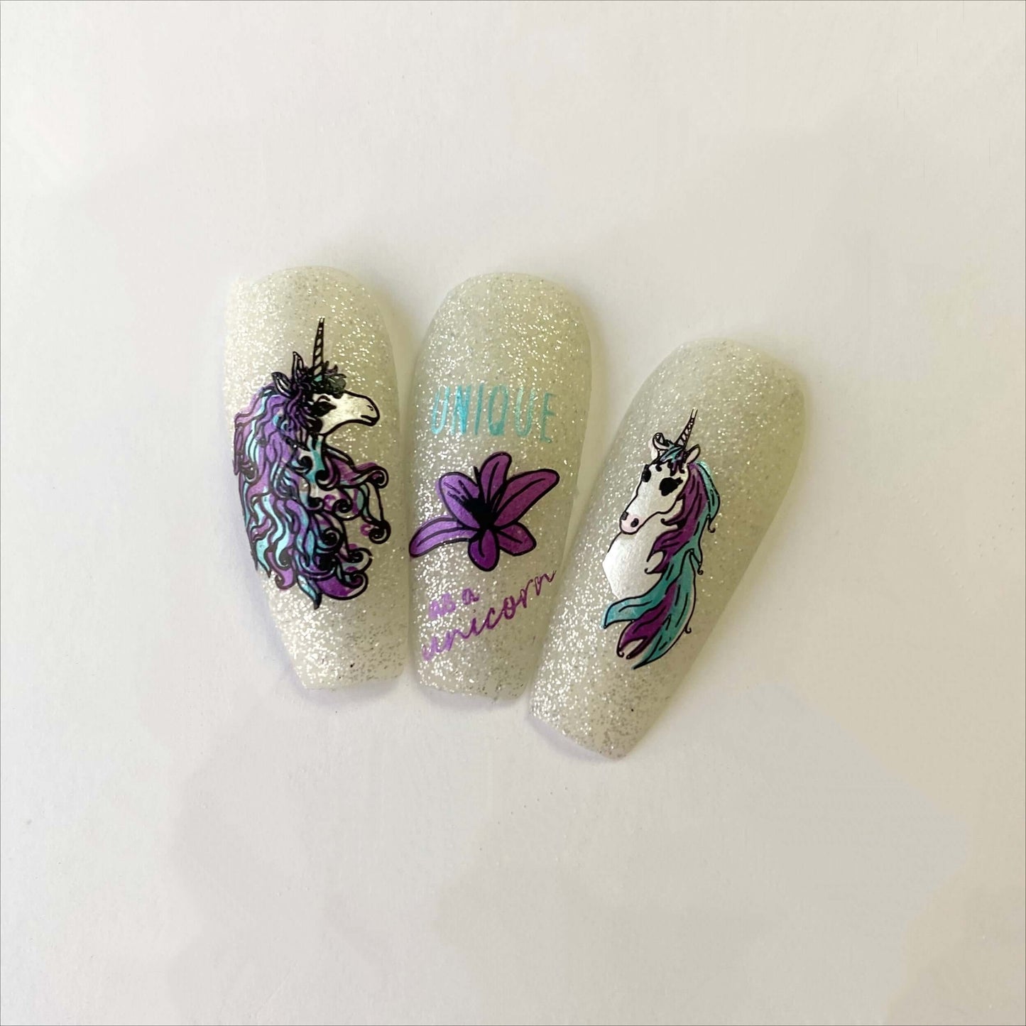 shimmering-manicured-nail-tips-showing-nail-art-designs-of-unicorns-and-a-lily