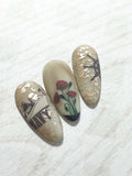 Three-nail-tips-showing-military-themed-nail-art-of-a-navy-ship-and-poppies