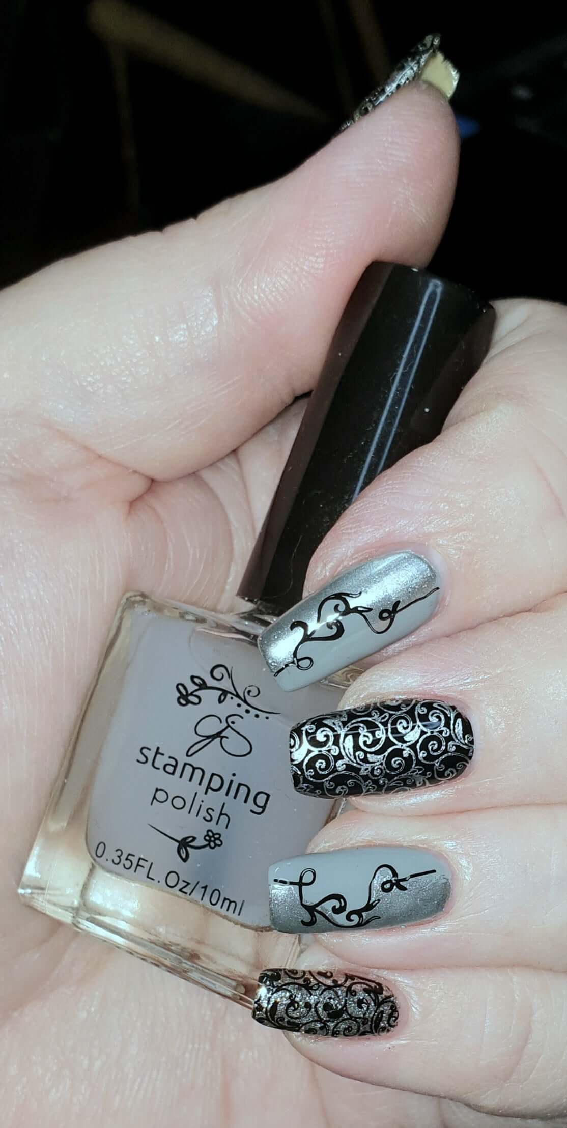 manicure-hand-holding-a-clear-jelly-polish-with-nail-art-designs-of-swirly-vines