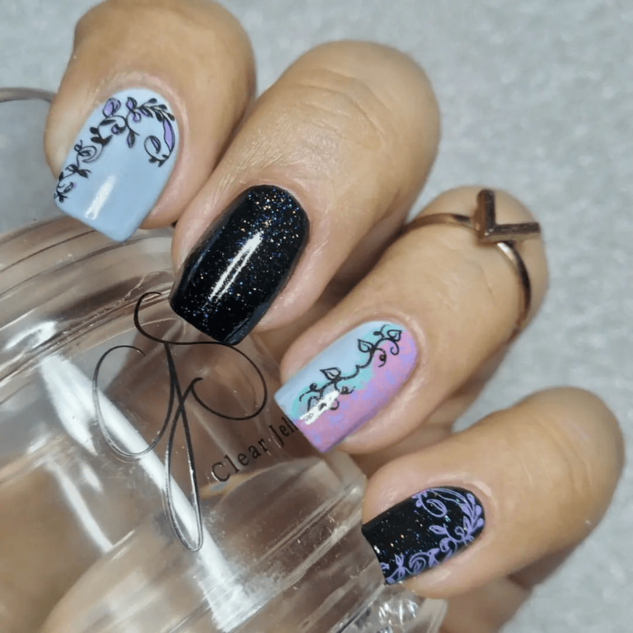 manicure-hand-holding-a-clear-jelly-stamper-with-nail-art-designs-of-swirly-vines