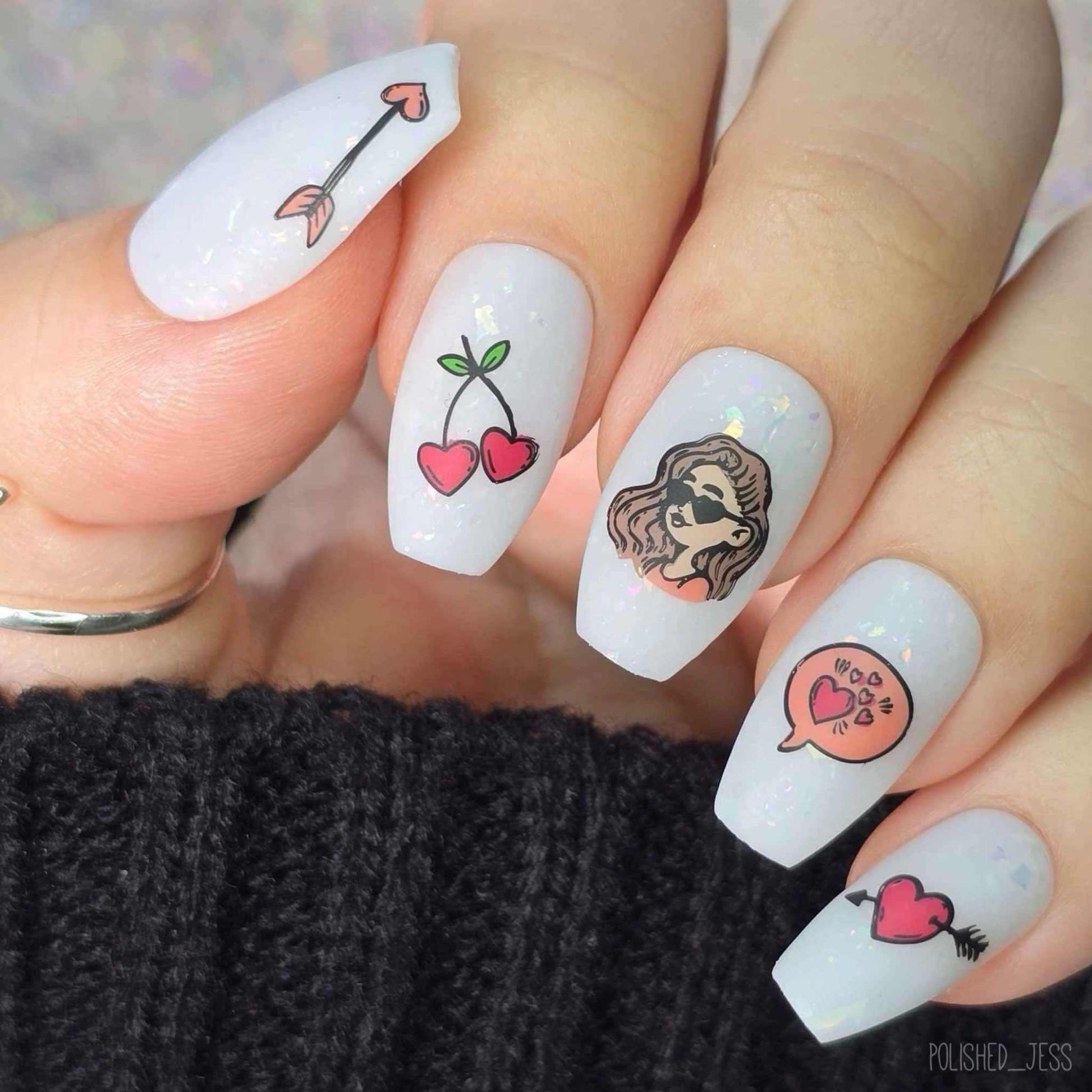 manicured-hand-showing-nail-art-designs-of-heart-cherries-heart-arrow-and-a-girl-wth-heart-glasses