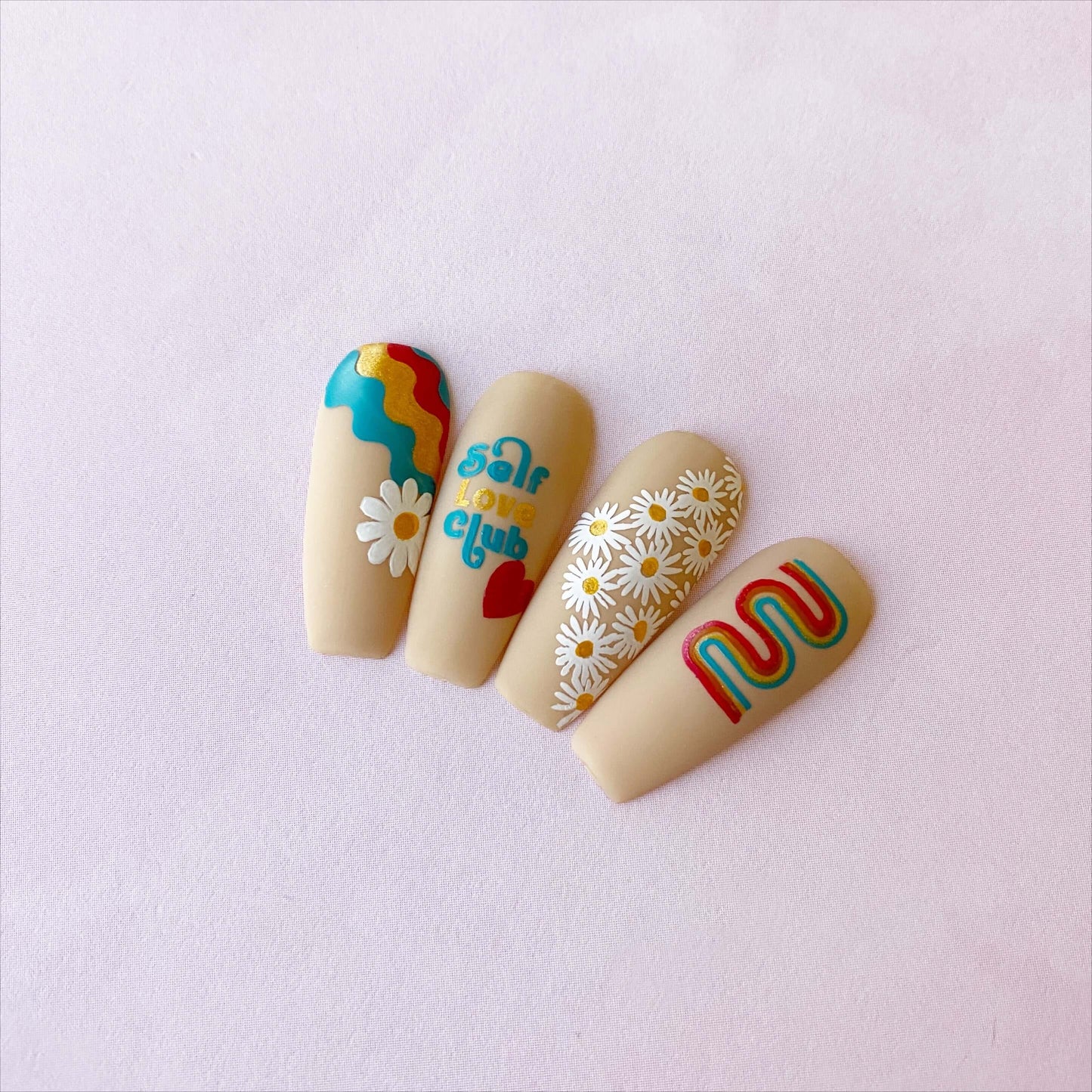 set-of-manicured-nail-tips-with-nail-art-designs-of-daisies-retro-waves-and-the-words-self-love-club
