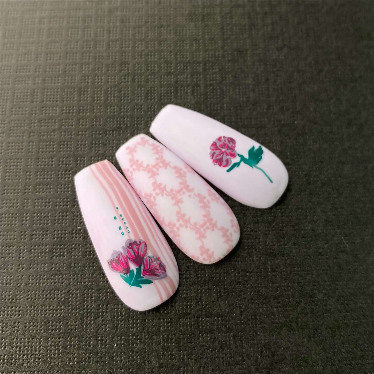 three-manicured-nail-tips-showing-delicate-nail-art-designs-of-flowers-and-full-coverage-patterns