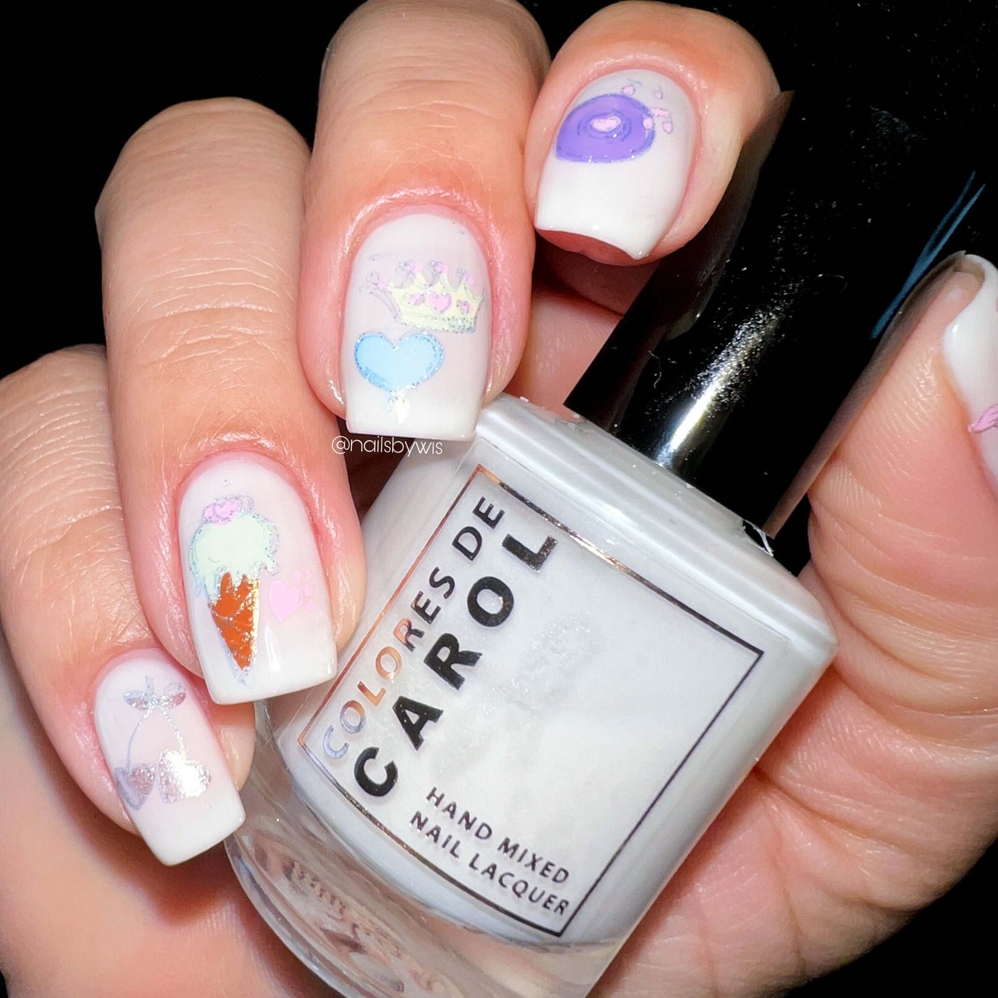 manicured-hand-holding-a-nail-polish-with-layered-nail-art-designs-of-ice-cream-cone-heart-cherries