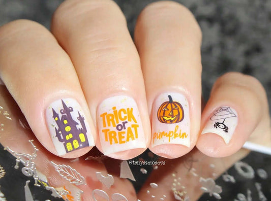 manciured-hand-holding-a-steel-stamping-plate-with-nail-art-designs-of-a-pumpkin-hanuted-house-and-spider-web