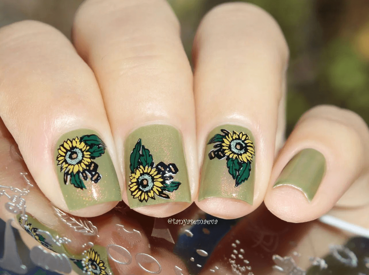 manciured-hand-holding-a-steel-stamping-plate-with-nail-art-designs-of-sunflowers