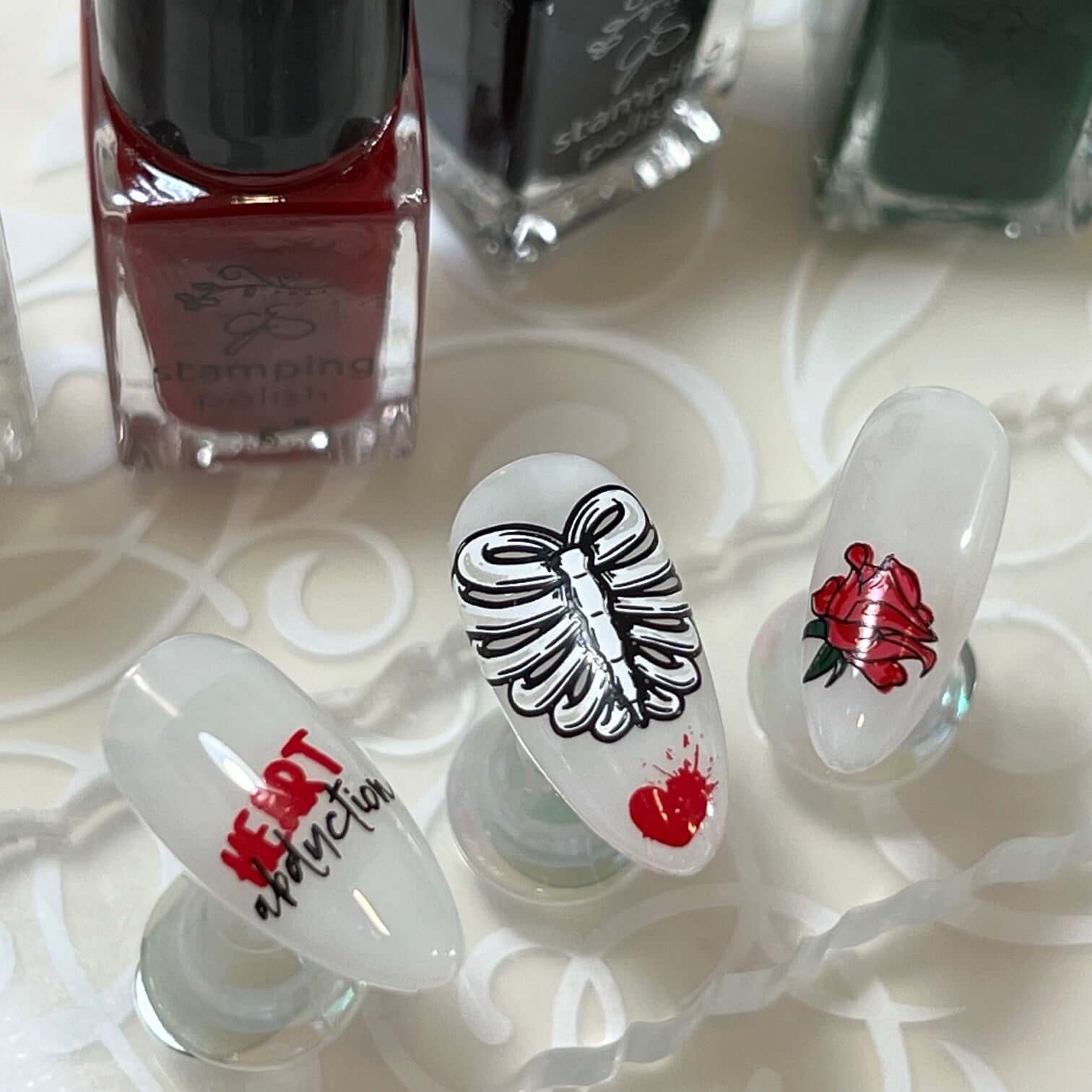 set-of-three-nail-tips-with-creepy-valentines-nail-art-designs-of-a-blood-splat-heart-rose-and-words-heart-abduction