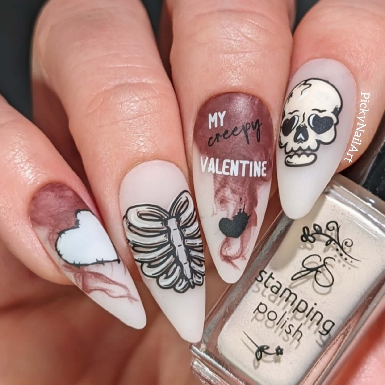 manicured-hand-with-layered-nail-art-designs-of-a-skull-rib-cage-barbwire-heart-and-words-my-creepy-valentine-holding-a-polish-bottle