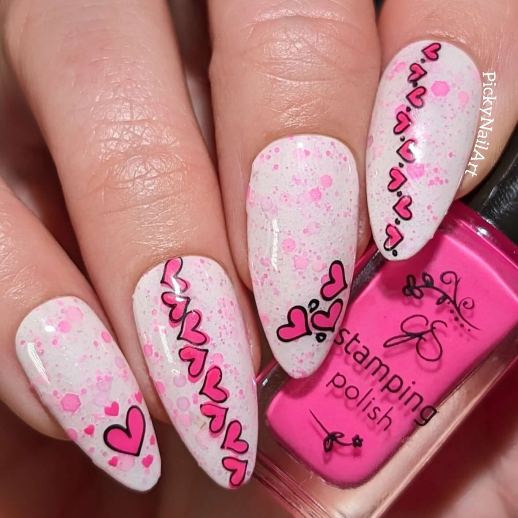 manicured-hand-with-nail-art-designs-of-little-cartoon-hearts-holding a bottle of-stamping-polish