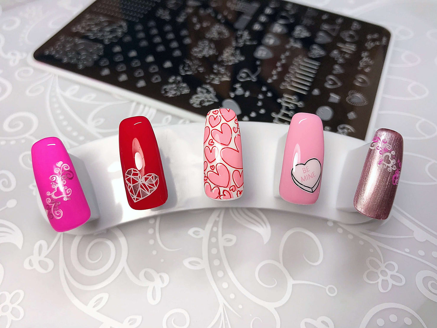 set-of-nail-tips-with-valentines-themed-nail-art-designs-of-different-sized-hearts-and-the-words-be-mine