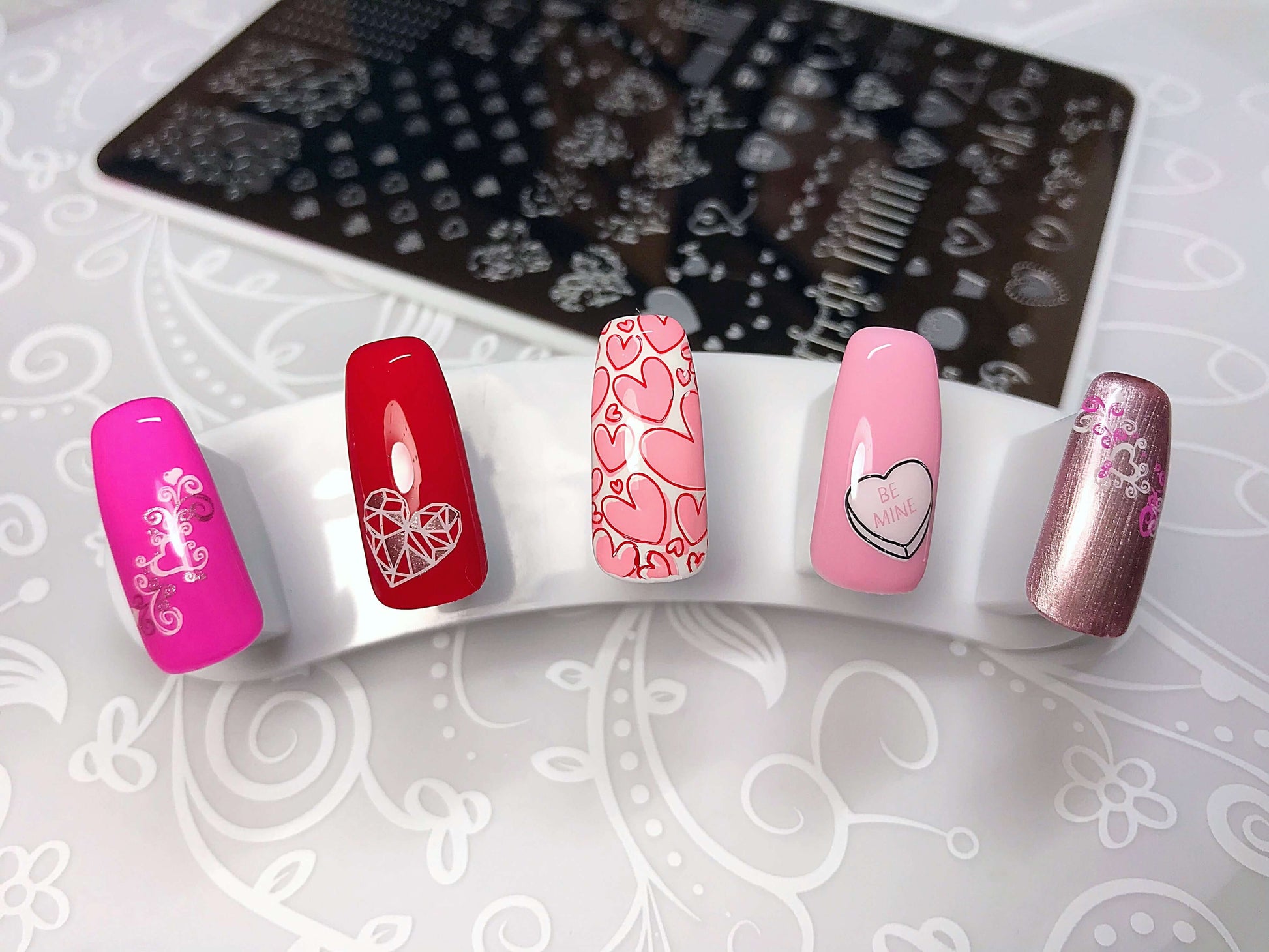 set-of-nail-tips-with-valentines-themed-nail-art-designs-of-different-sized-hearts-and-the-words-be-mine