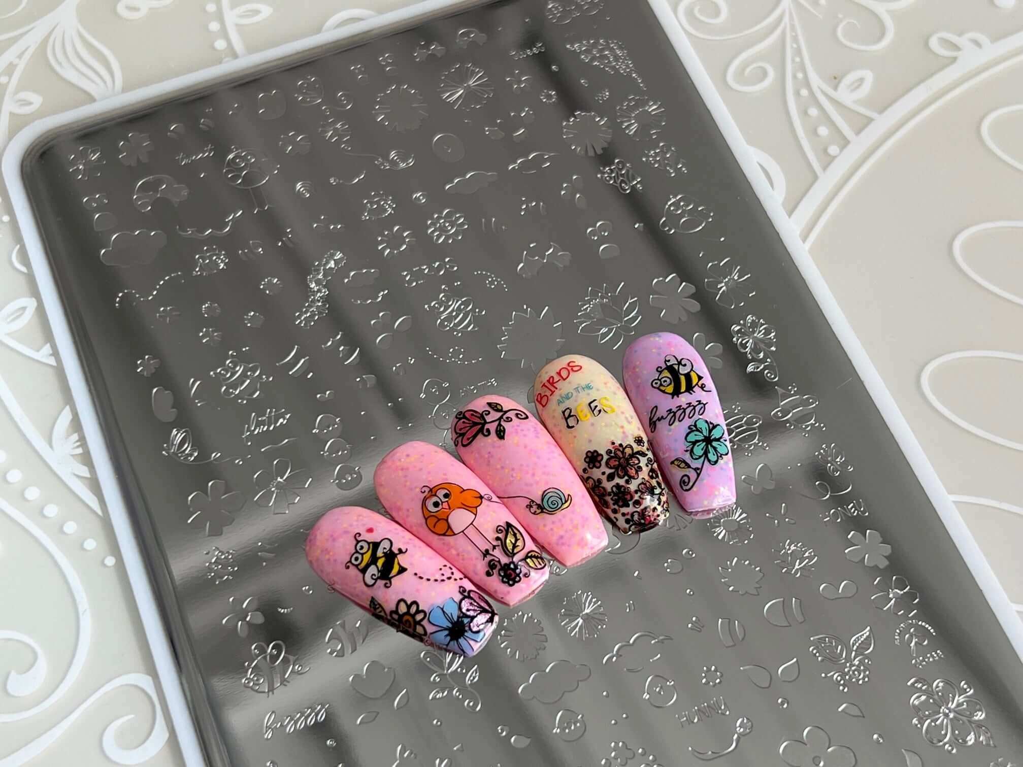 set-of-manicure-nail-tips-with-layered-nail-art-designs-of-cartoon-bees-birds-flowers-and-a-snail
