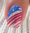 Single-manicured-nail-showing-nail-art-designs-of-stars-and-stripes-flag-in-a-distressed-style