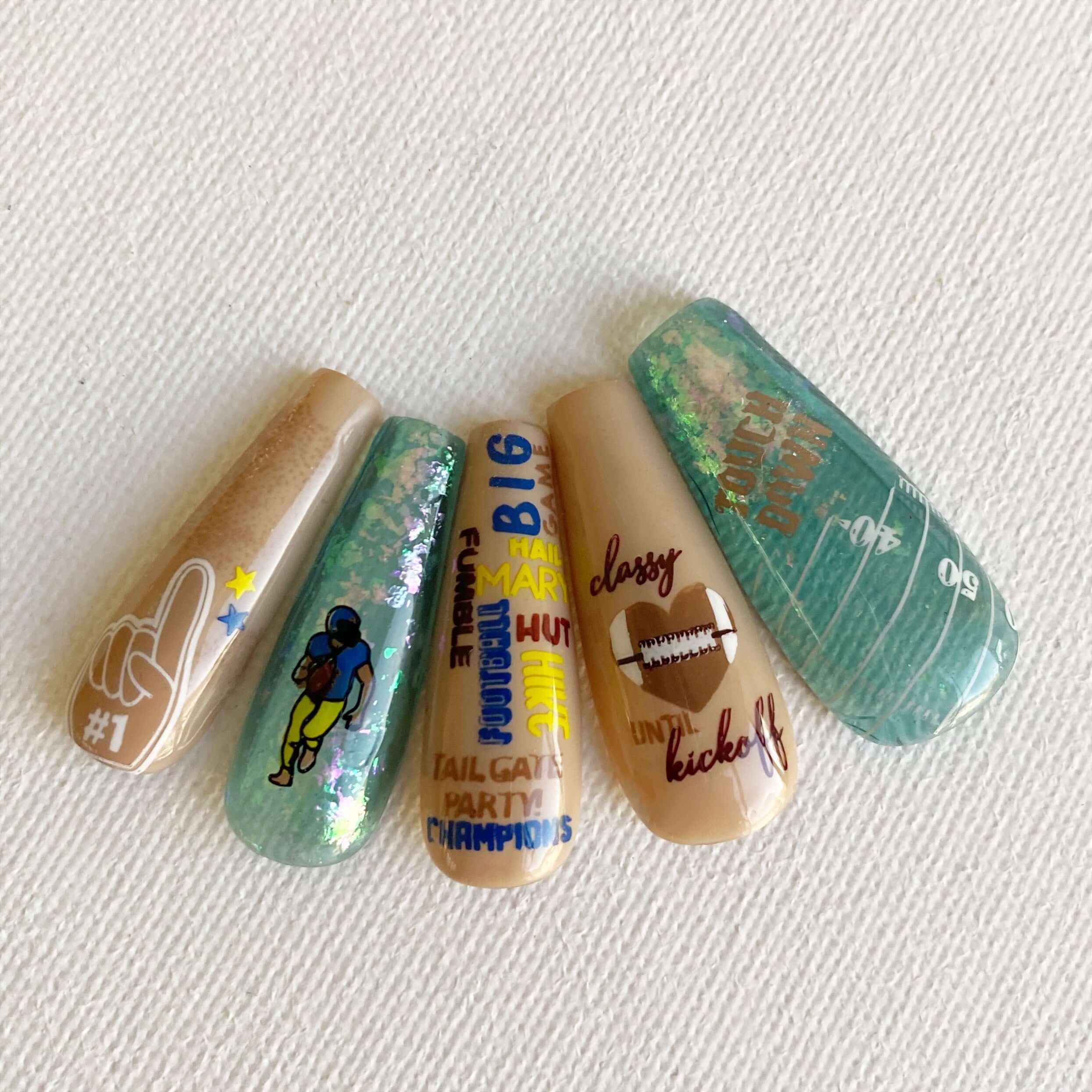 set-of-nail-tips-with-layered-nail-art-stamping-designs-of-a-football-field-lines-and-the words-touchdown