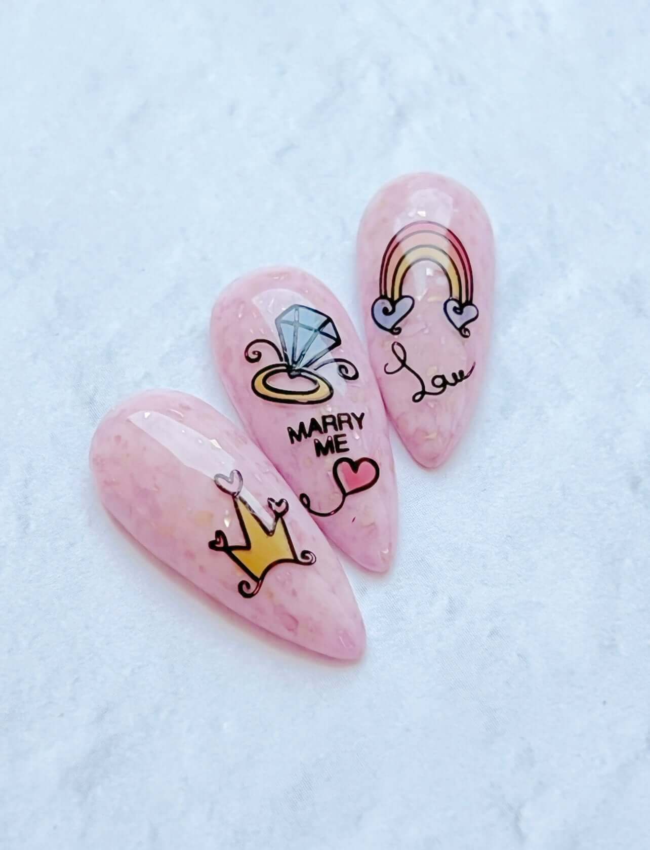set-of-three-nail-tips-with-nail-art-designs-of-a-diamond-ring-rainbow-and-words-marry-me
