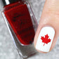 single-manicured-nail-showing-a-maple-leave-in-nail-art-with-a-bottle-of-red-stamping-polish